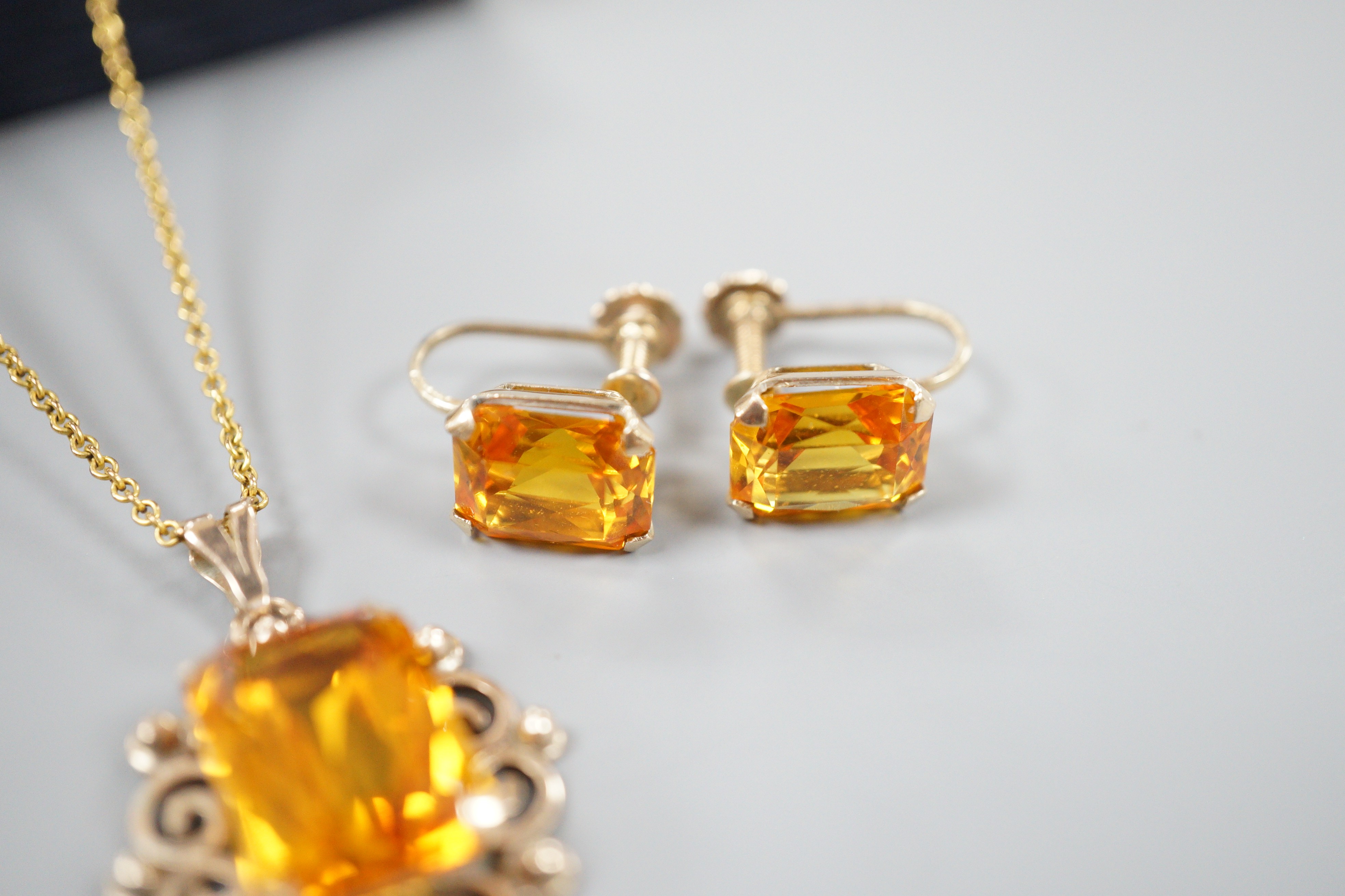 A yellow metal and citrine set pendant, 29mm, on a gold plated chain and a pair of 9ct and citrine set ear clips, gross 8.2 grams.